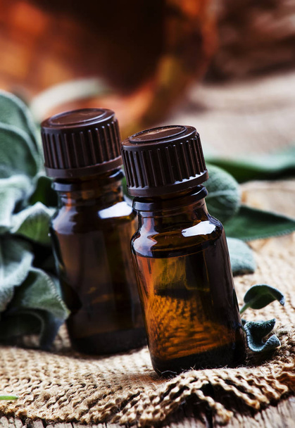 Essential sage oil in brown bottle on the vintage wooden blackground, rustic style, selective focus - Foto, immagini