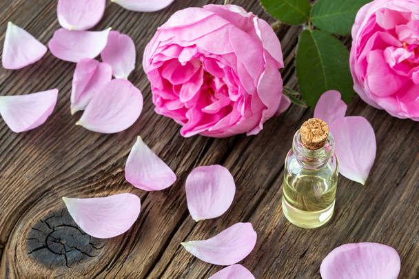 Butelka olejku z świeże róże na podłoże drewniane - Zdjęcie, obraz