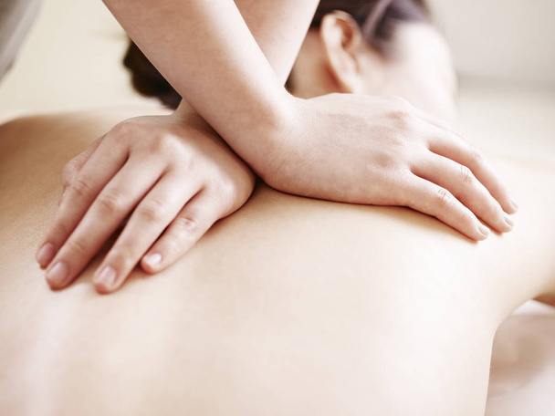 primo piano di mani di una massaggiatrice massaggiando indietro di una giovane donna asiatica
. - Foto, immagini