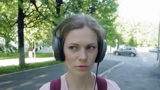 young stylish beautiful woman, on city streets listening to music in large monitor headphones. - Video, Çekim