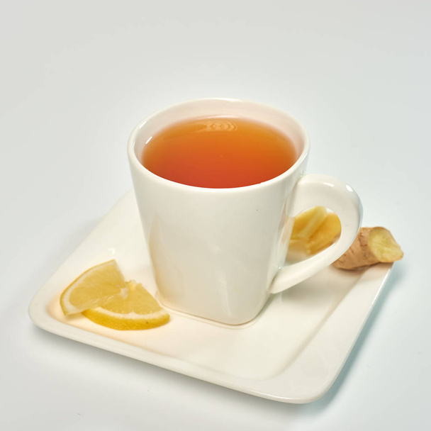 Tee mit Zitrone und Ingwer. Tee in einer weißen Tasse mit Zitrone und Ingwer. isoliert auf weißem Hintergrund. - Foto, Bild