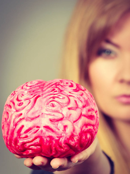 Blonde woman holding brain having something on mind, thinking of solution idea. - Foto, Imagen