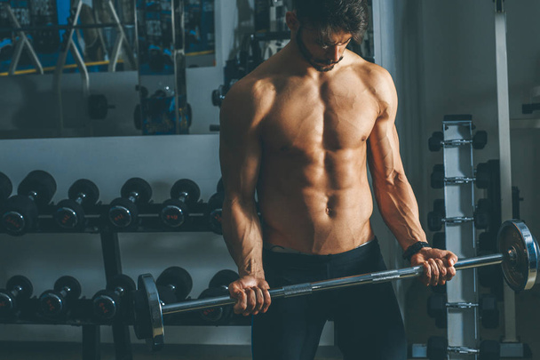 Retrato de un joven fuerte y guapo haciendo ejercicio con pesas
 - Foto, imagen