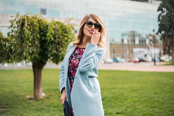 attraktive junge blonde Frau mit Sonnenbrille und posiert in der modernen Stadt - Foto, Bild