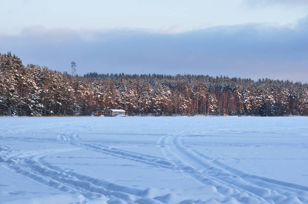Snowmobile trail on a snowy frozen lake against the forest - 写真・画像