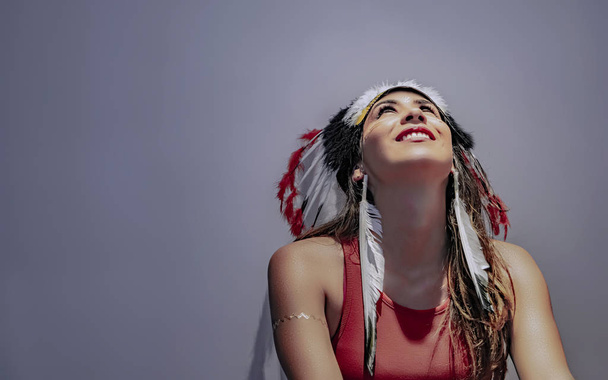 Портрет латинской модели с пернатым головным убором с подсветкой и тенями на лице
 - Фото, изображение