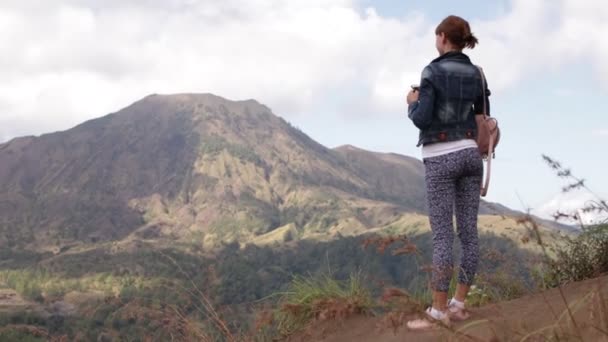 Молода жінка з смартфон і рюкзак на тлі мальовничого гірського. Вулкан Батура, Балі. - Кадри, відео