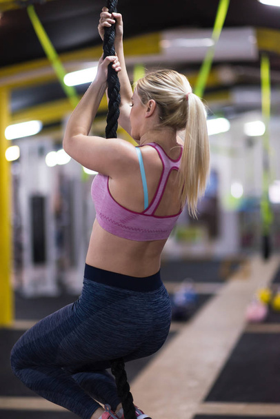 young muscular woman doing rope climbing in cross fitness gym - Foto, Imagem