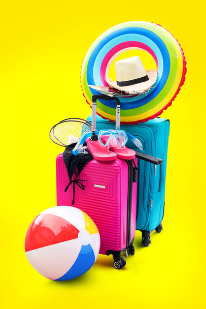Parlak bavul yaz aksesuarları şeyler terlik şapka maske Ballon raketler. Kavram yaz tatili seyahat aile gezisi arka plan sarı izole - Fotoğraf, Görsel