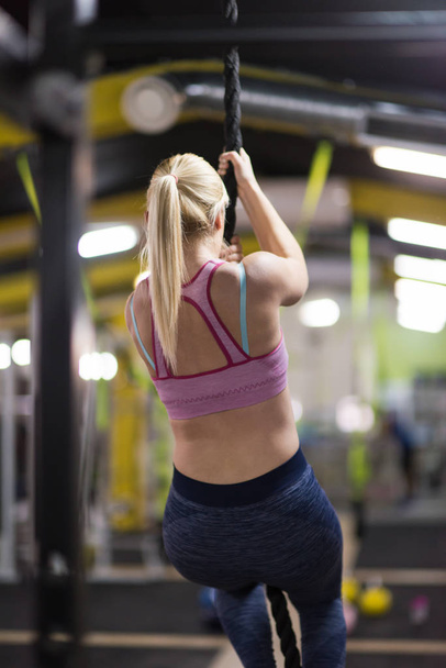 young muscular woman doing rope climbing in cross fitness gym - Zdjęcie, obraz