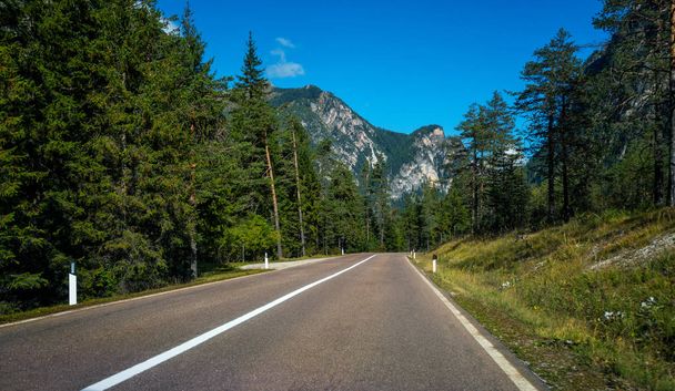 Hermoso camino de montaña con árboles, bosques y montañas en los fondos. Tomado en la carretera estatal de la montaña Dolomitas en Italia
. - Foto, Imagen