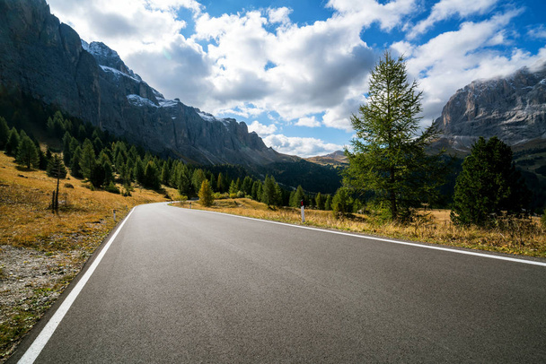 木、森の背景の山々 と美しい山岳道路。パッソ ガーデナ、イタリアのドロミテ山のセッラ山群の状態の高速道路の道路で撮影. - 写真・画像
