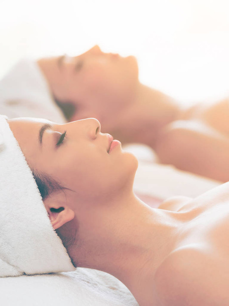 Relaxed young woman lying on spa bed prepared for facial treatment and massage in luxury spa resort. Wellness, stress relief and rejuvenation concept. - Photo, Image