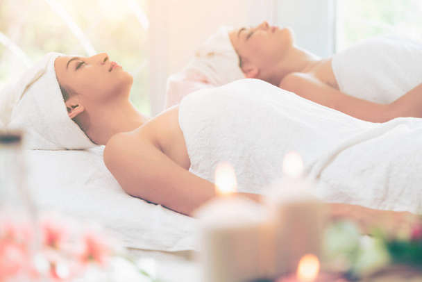 Mujer joven y relajada tumbada en una cama de spa preparada para el tratamiento facial y el masaje en un spa de lujo. Bienestar, alivio del estrés y concepto de rejuvenecimiento. - Foto, Imagen