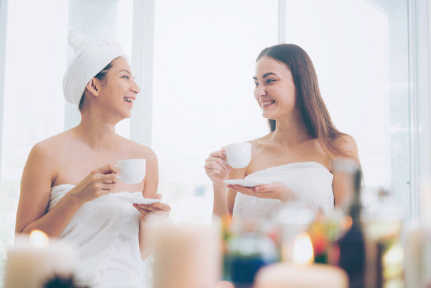 Két nő és ivott tea vagy növényi ital, miközben beszélgetést luxus day spa-ban. Wellness, szabadidős és egészségügyi koncepció. - Fotó, kép