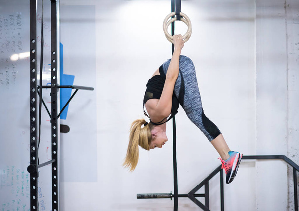 young athletic woman working out on gymnastic rings at the cross fitness gym - Foto, Imagem