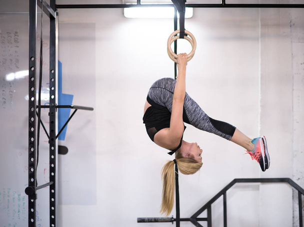 young athletic woman working out on gymnastic rings at the cross fitness gym - Photo, Image