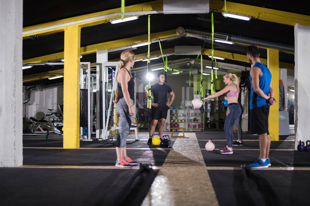 group of healthy young athletes doing exercises with kettlebells at cross fitness studio - Zdjęcie, obraz