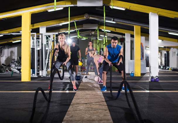 young fit sports couple working out in functional training gym doing  battle ropes cross fitness exercise - Foto, Imagen
