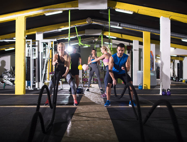 young fit sports couple working out in functional training gym doing  battle ropes cross fitness exercise - Foto, imagen