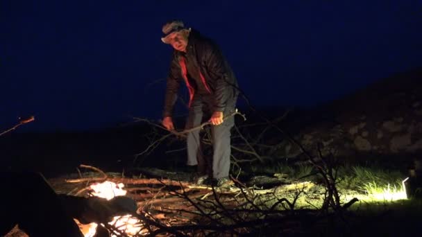 Зрелый человек ломает и срезает сухую ветку дерева для костра в горах ночью. Активные люди Traveler
 - Кадры, видео