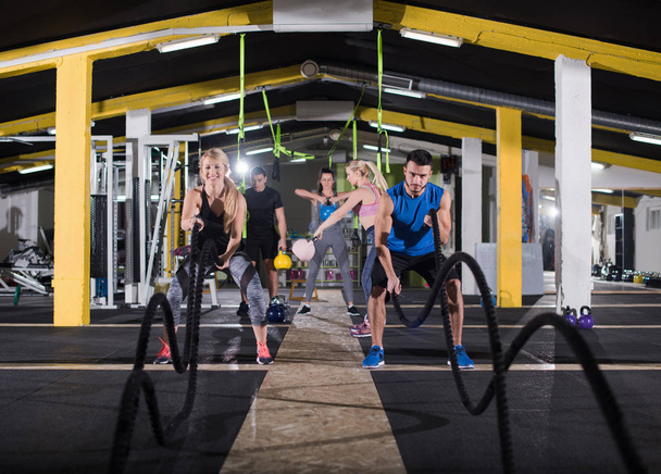 young fit sports couple working out in functional training gym doing  battle ropes cross fitness exercise - Foto, Bild