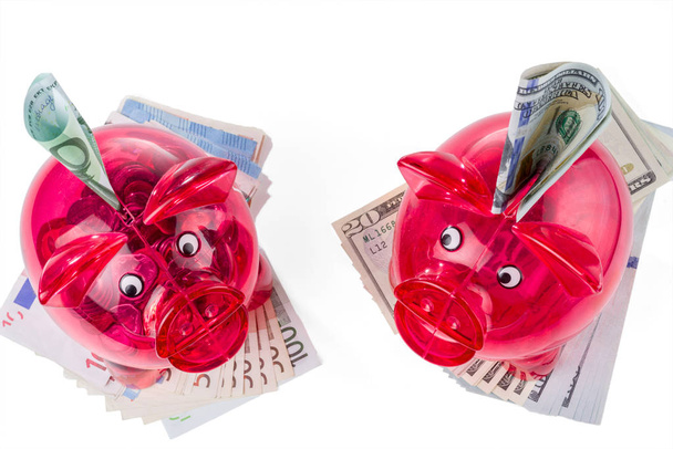 Hucha roja transparente con billetes en dólares y en euros. Diversificación de las inversiones
. - Foto, Imagen