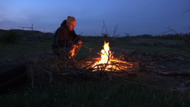 Зрелый человек ломает и режет сухую ветку дерева для костра в горах ночью. Активные люди Traveler
 - Кадры, видео
