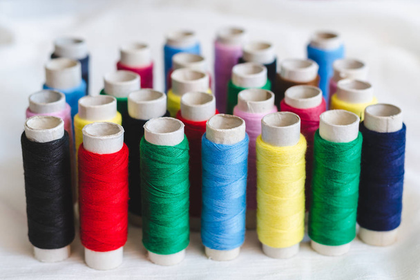 Group of colored thread spools on white cotton cloth - Fotoğraf, Görsel
