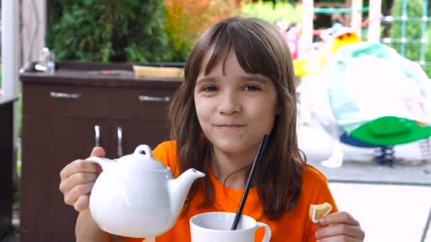 Κοριτσάκι ρίχνει τσάι για τη χωροθέτηση κύπελλο καφέ. - Πλάνα, βίντεο