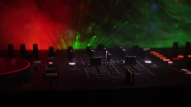 In selective focus of Pro dj controller.The DJ console deejay mixing desk at music party in nightclub with colored disco lights. Close up view - Footage, Video