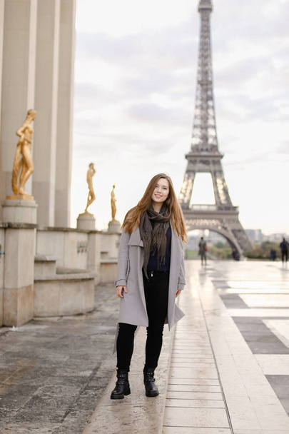 Młoda kaukaski kobieta stojąc na placu Trocadero, niedaleko złoconych posągów i Wieża Eiffla. - Zdjęcie, obraz
