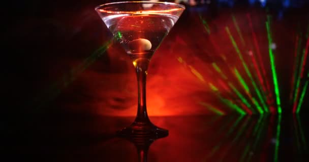bicchiere con martini all'interno con olive. Vista da vicino di vetro con drink club su sfondo scuro nebbioso tonica. Concentrazione selettiva. Club drink concetto
 - Filmati, video