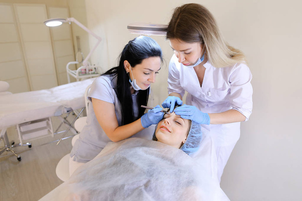 Cosmétologue caucasien et infirmière tatouant les sourcils
. - Photo, image