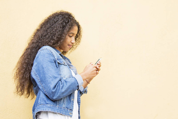 african girl using cellphone with yellow background - Foto, Imagen