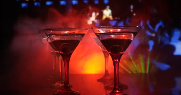 Useita laseja kuuluisa cocktail Martini, ammuttiin baarissa tumma sävyinen sumuinen tausta ja disko valot. Klubin juomaidea. Valikoiva painopiste
 - Materiaali, video