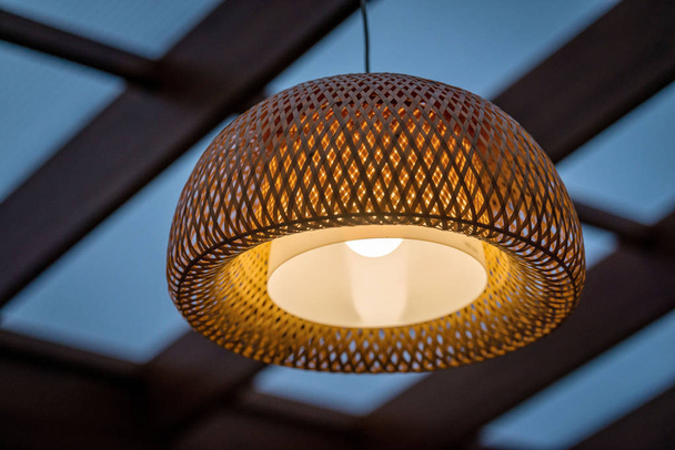 Interior of the outdoor terrace with a wicker wood ceiling lamp. - Фото, изображение