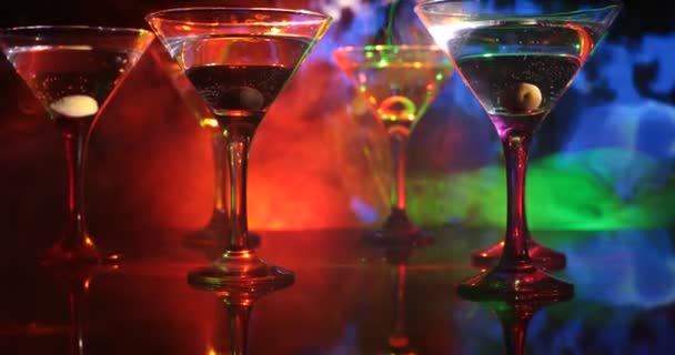 Varias copas de famoso cóctel Martini, disparado en un bar con fondo de niebla de tonos oscuros y luces de discoteca. Concepto de bebida del club. Enfoque selectivo
 - Metraje, vídeo