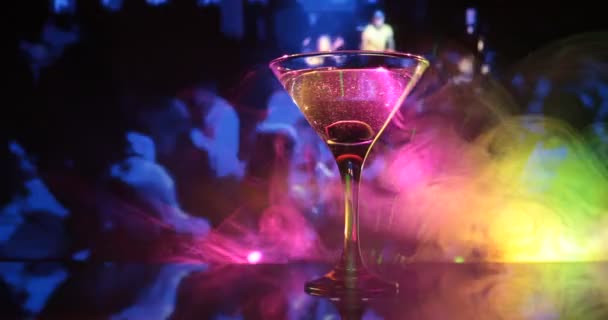 glas met martini met olijf erin. Close-up zicht op glas met club drankje op donkere mistige achtergrond. Selectieve focus. Clubdrankconcept - Video