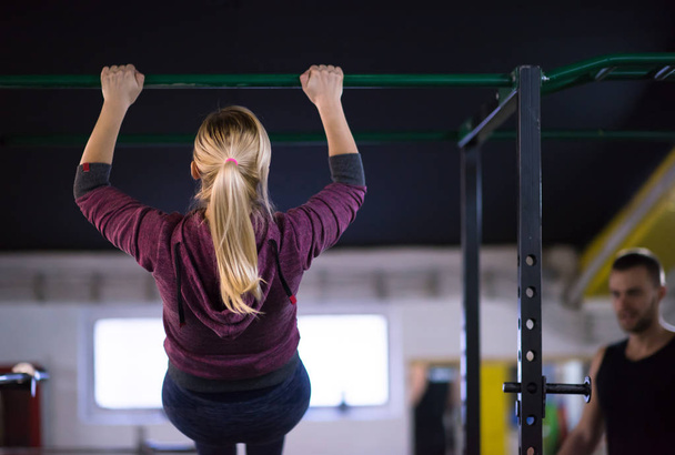 jeune femme musclée faisant des pull-ups sur la barre horizontale dans le cadre de la formation Cross fitness - Photo, image
