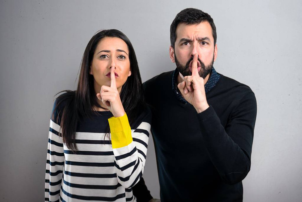 Couple faisant un geste de silence sur fond gris
 - Photo, image