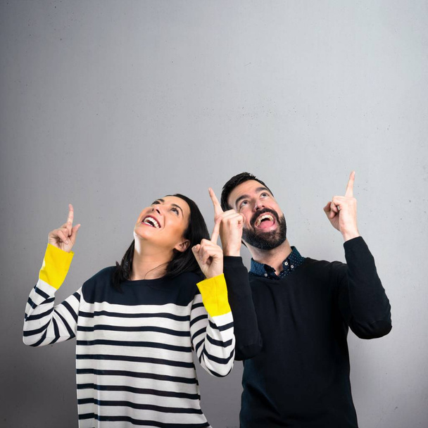 Couple pointing up on grey background - Photo, Image