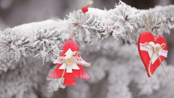 Красные деревянные рождественские игрушки сердце и елка висят на ветвях снежной елки. Видеодвижение
 - Кадры, видео