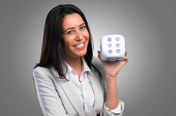 Pretty woman holding a dice on grey background - Φωτογραφία, εικόνα
