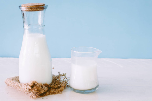 Une bouteille de lait et un verre de lait sur une table en bois
 - Photo, image