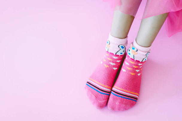 Nuori tyttö ja jalat vaaleanpunaisissa sukissa vaaleanpunaisella taustalla
 - Valokuva, kuva