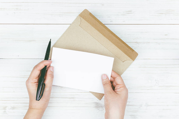 Mão segure um envelope e papel no fundo de madeira
 - Foto, Imagem