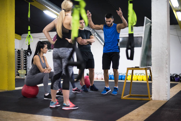 Training course.group of young athletes getting instructions from trainer before exercise at cross fitness gym - Foto, imagen