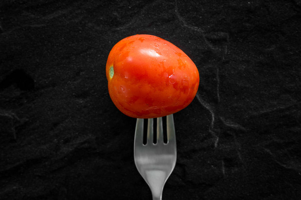 Pomodoro con forchetta su fondo nero
 - Foto, immagini