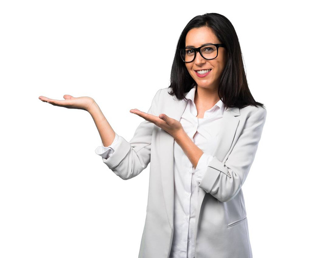 Mujer bonita con gafas presentando algo sobre fondo blanco
 - Foto, Imagen